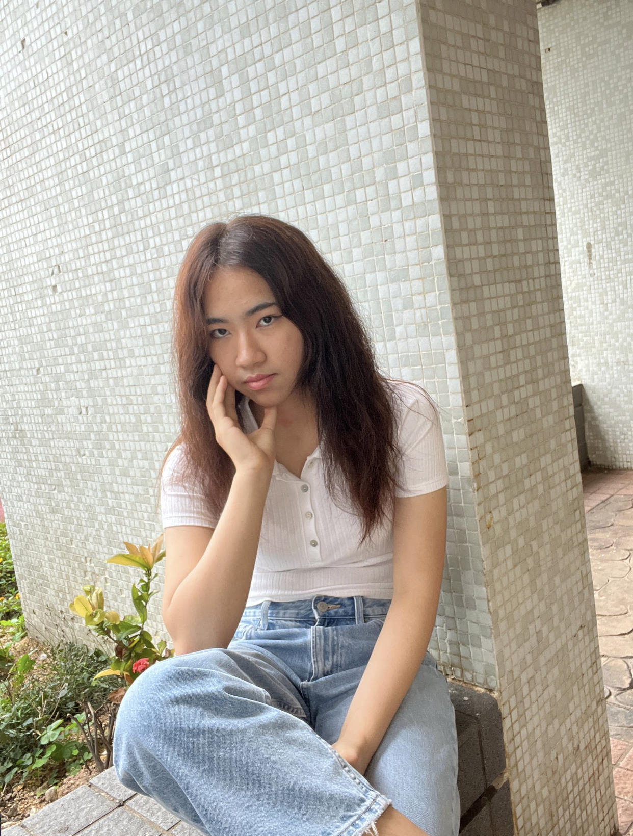 A portrait of Liana Tang, an Asian teen girl, sitting against a tiled wall.